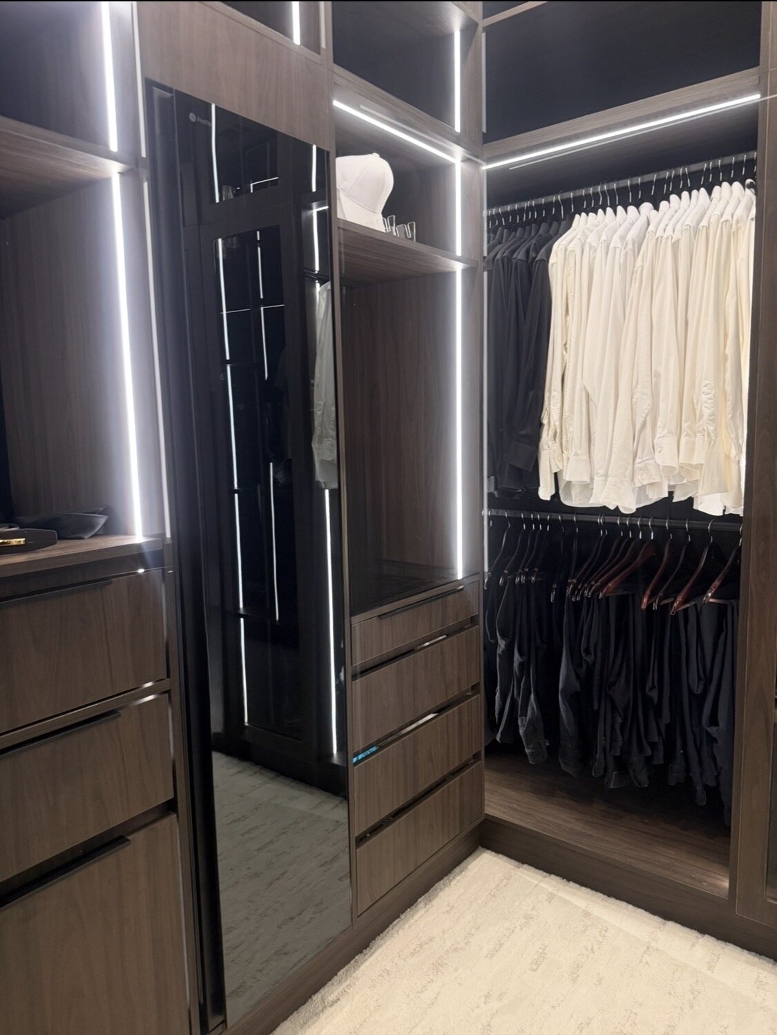 Custom walk-in closet with drawers mirror hanging areas and LED lighting